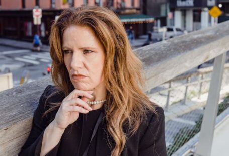 Considerations - Businesswoman Leaning against Railing in a City and Calculating Business Risk