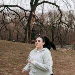 Rotational Dynamics - Full body motivated plus sized female in gray hoodie running in autumn park