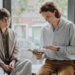 Explanations - Man in Blue Dress Shirt Sitting Beside Woman in Gray Blazer