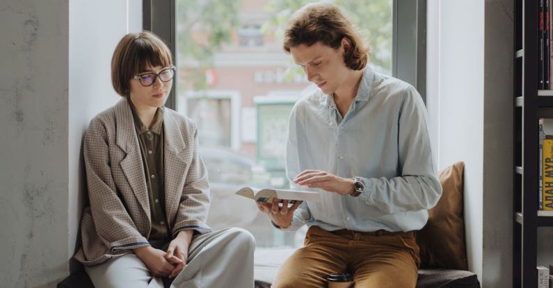 Explanations - Man in Blue Dress Shirt Sitting Beside Woman in Gray Blazer