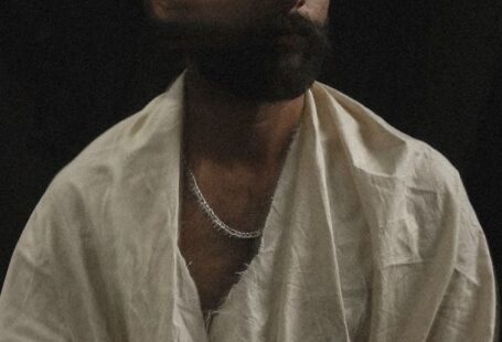 Cognitive Abilities - Long exposure of Asian male living with psychological disorder in white worn out robe sitting on floor and moving head against black background